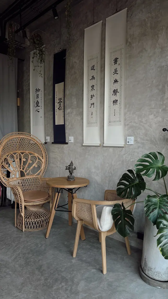 Rattan peacock chair and calligraphy scrolls on a concrete wall